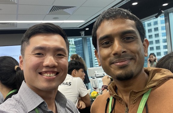 Two men pose smiling at a conference