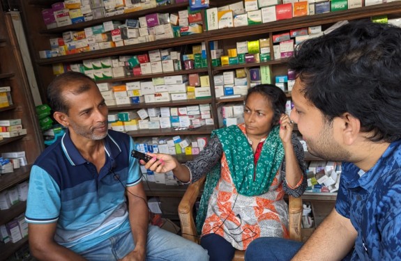 A woman interviews pharmacy workers in Bangladesh