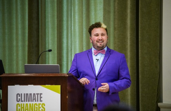 A man in a bright purple suit speaks during a conference